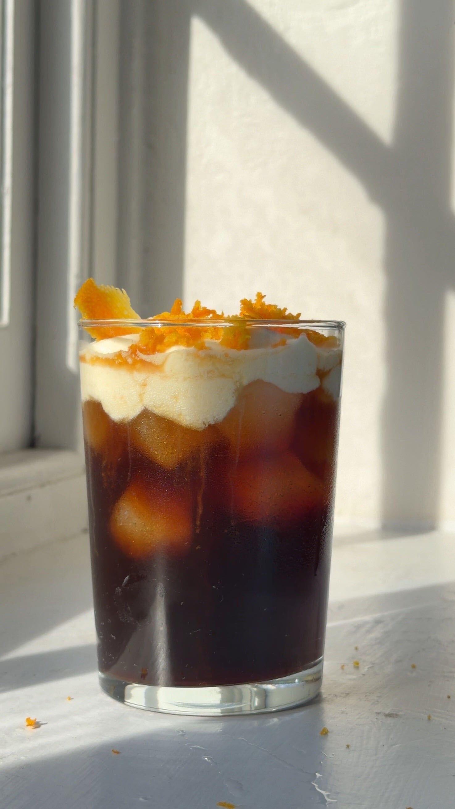 Mont Blanc orange cold foam iced coffee in a glass with orange zest garnish